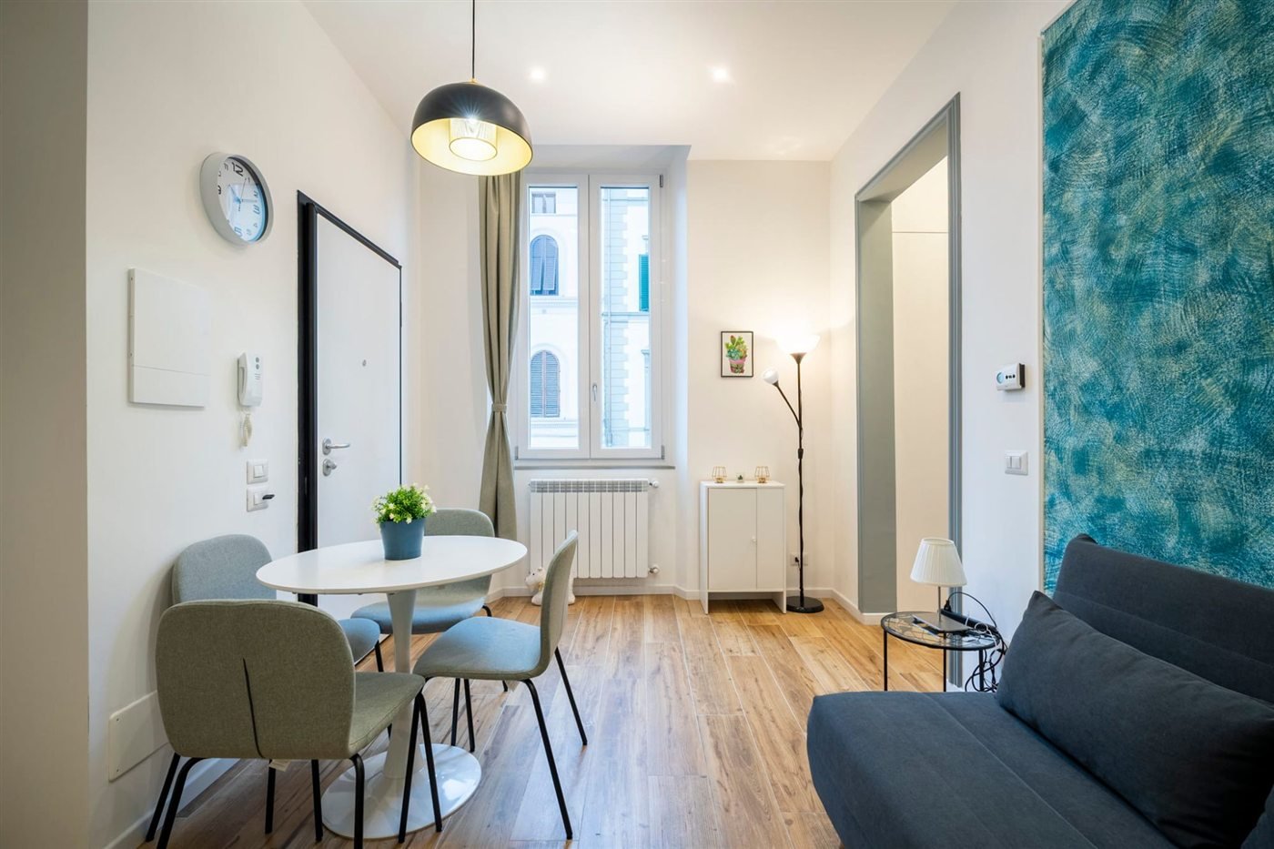 Bright living room with a round dining table and a teal feature wall