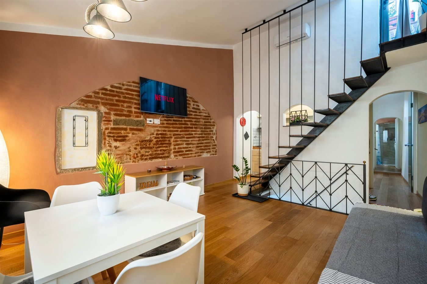 Living room with exposed brick arch and a floating staircase